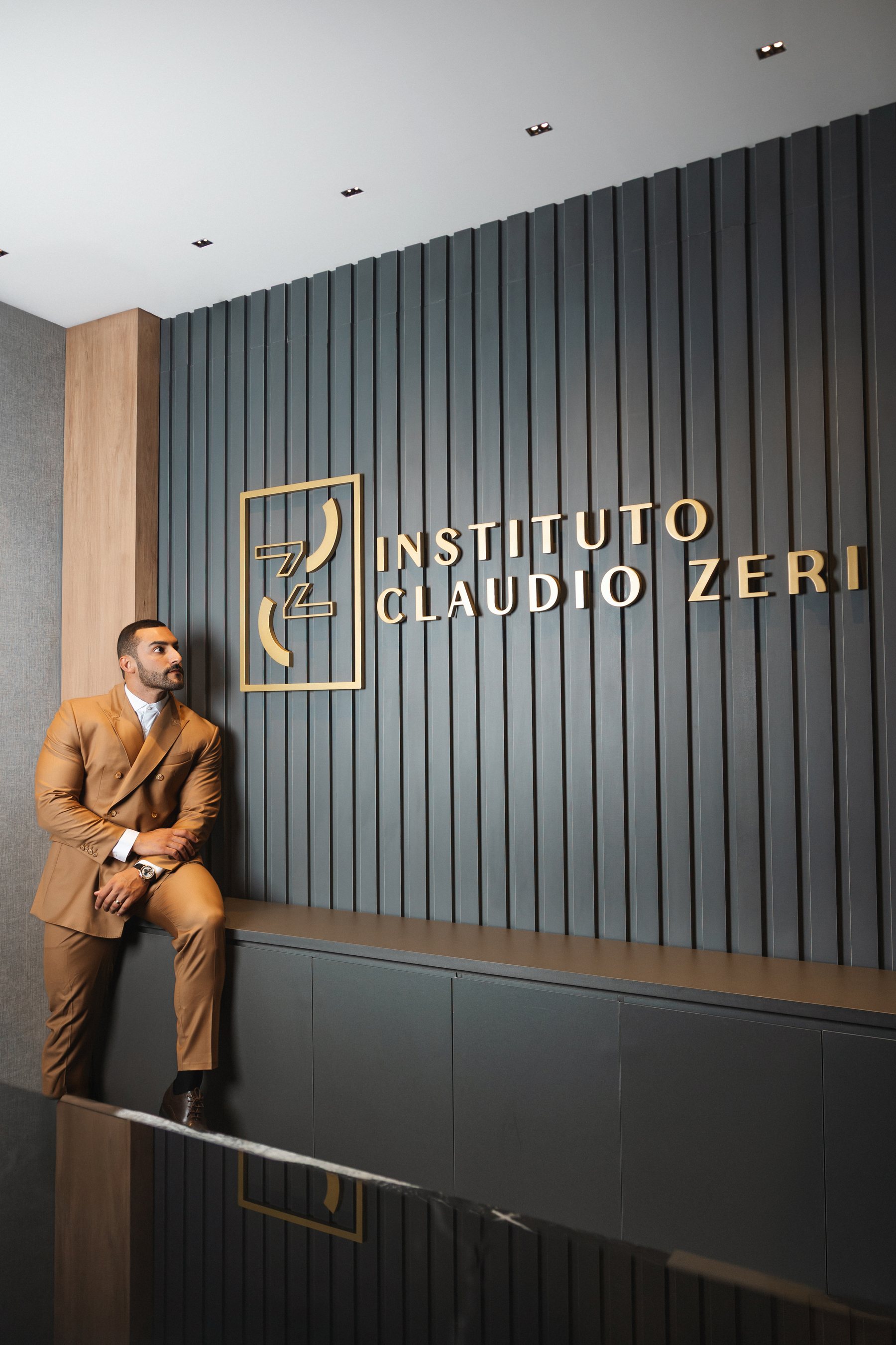 Dr. Claudio Zeri em pé, junto à identidade visual do Instituto Claudio Zeri.